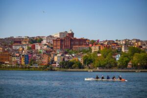 Lively Istanbul waterfront Fener and Balat, Golden Horn with rowers showcasing vibrant architecture on a sunny day.