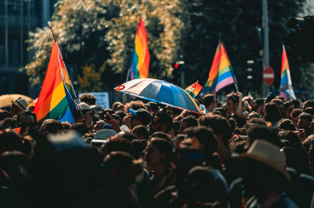 Crowd celebrating LGBT Pride with rainbow flags in outdoors.